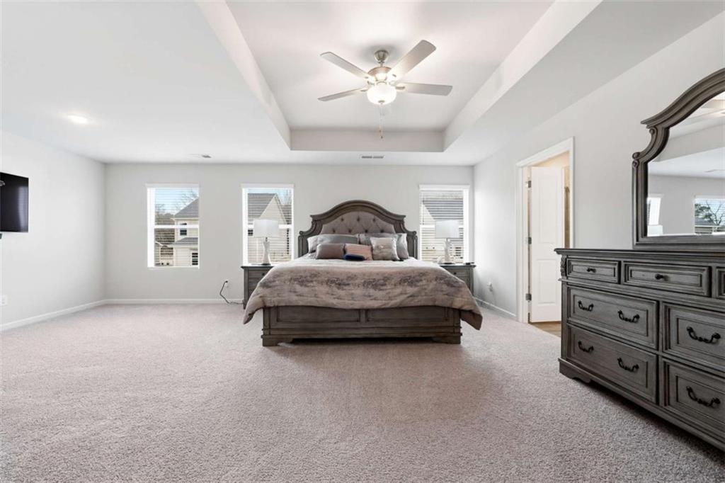 11817 Rizvan Place Covington, GA 30014 - Photo 17 of 40 a spacious bedroom with a bed and a chandelier