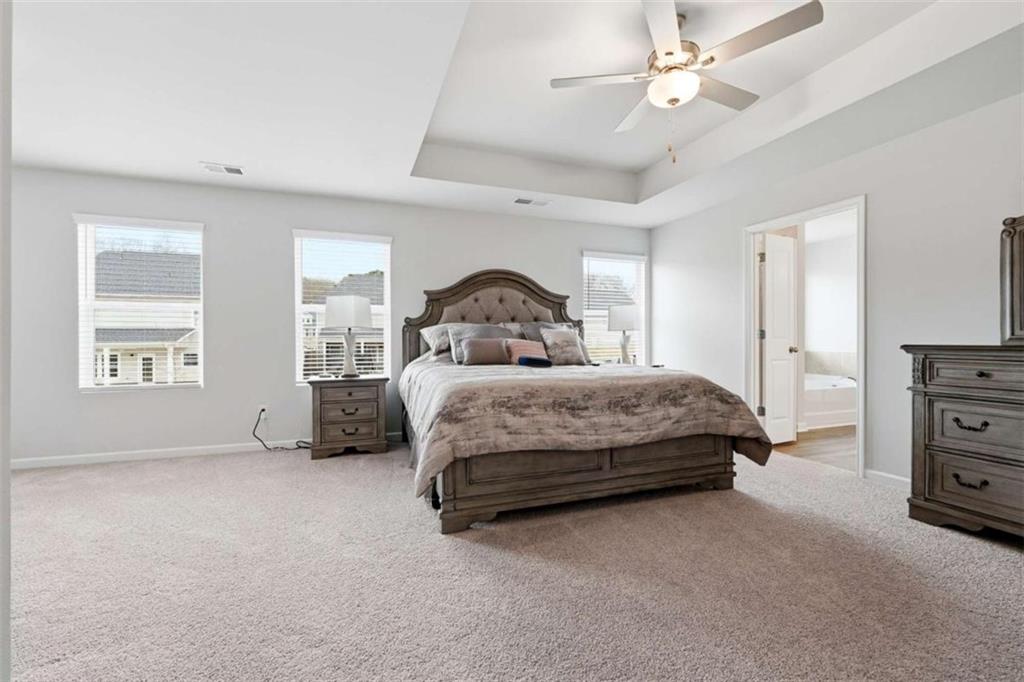 11817 Rizvan Place Covington, GA 30014 - Photo 20 of 40 a spacious bedroom with a bed and a chandelier