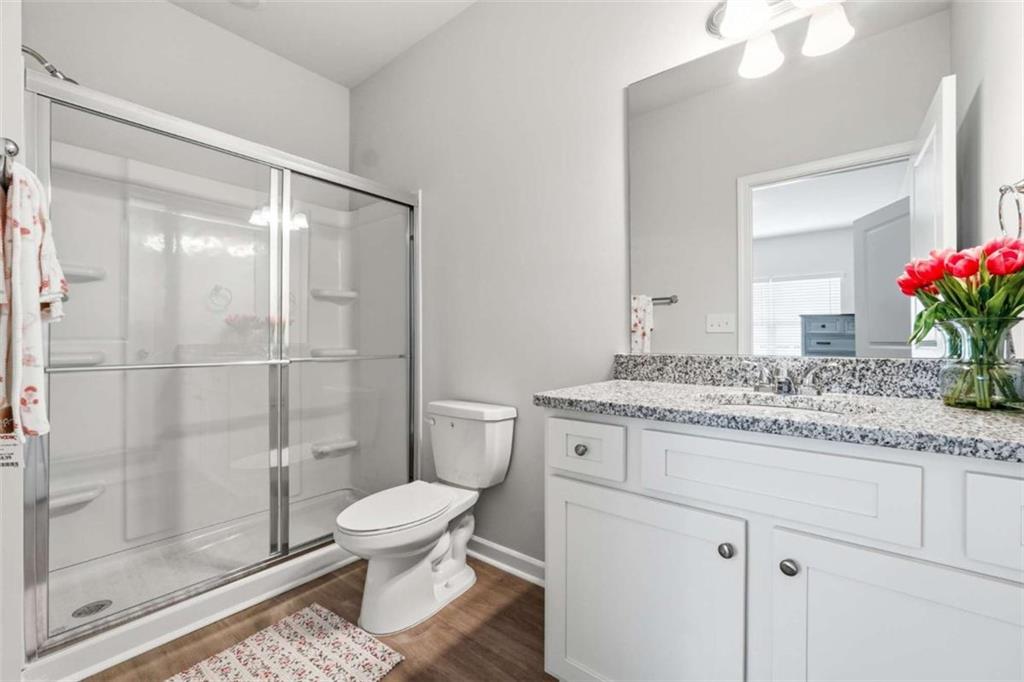 11817 Rizvan Place Covington, GA 30014 - Photo 26 of 40 a bathroom with a granite countertop sink toilet a mirror and shower