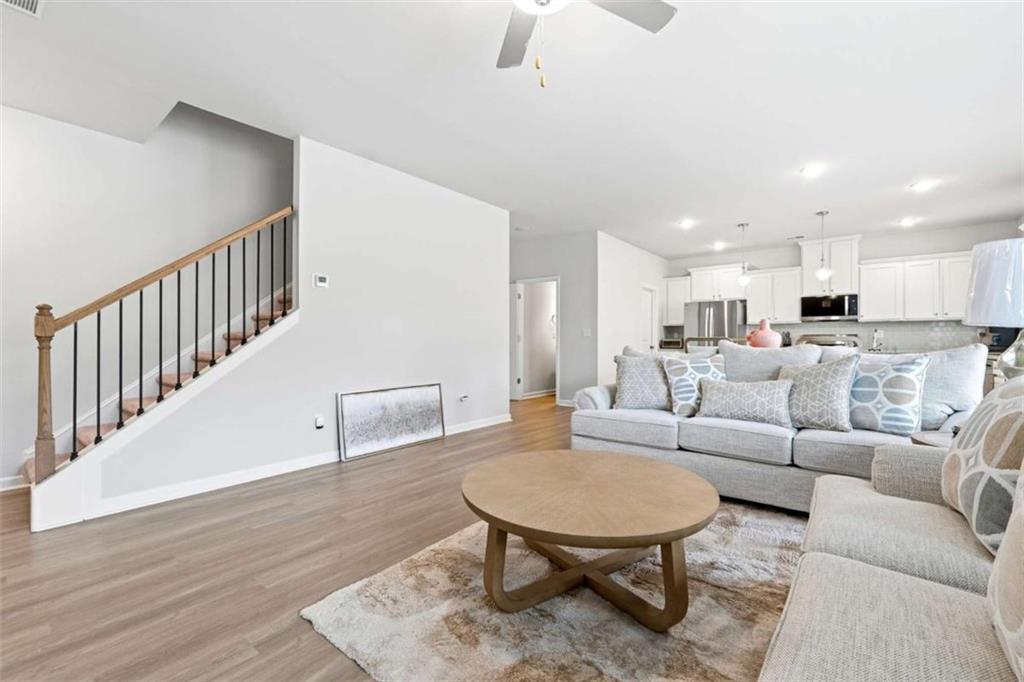 11817 Rizvan Place Covington, GA 30014 - Photo 7 of 40 a living room with furniture and a dining table with wooden floor