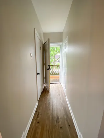 a view of a hallway with wooden floor and a window
