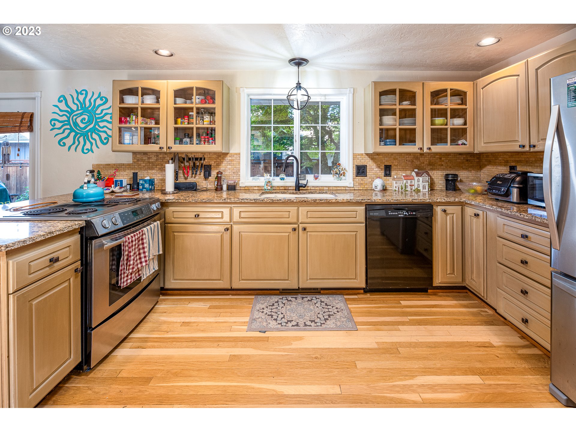 6796 F Street Springfield, OR 97478 - Photo 8 of 35 a large kitchen with stainless steel appliances granite countertop a stove a sink dishwasher and cabinets with wooden floor