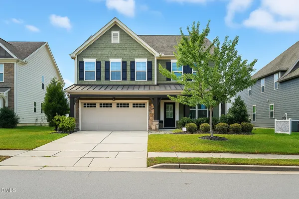 a front view of house with yard and trees in the background