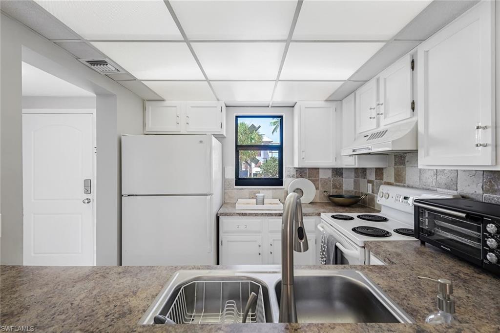 807 River Point Drive, Unit 102D Naples, FL 34102 - Photo 7 of 32 a kitchen with stainless steel appliances granite countertop a refrigerator a stove a sink and white cabinets