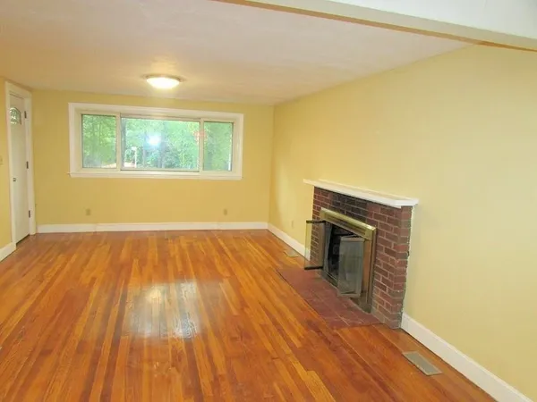 a view of empty room with wooden floor and fireplace