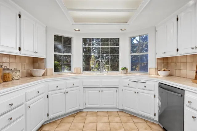 a kitchen with white cabinets and sink