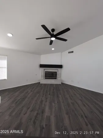 an empty room with wooden floor ceiling fan and windows