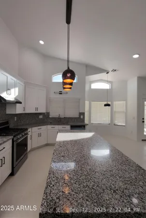 a kitchen with stainless steel appliances granite countertop a sink a stove and a refrigerator