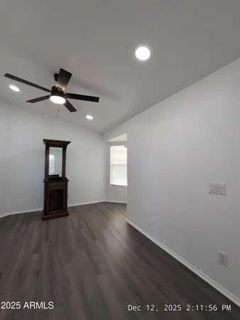 an empty room with wooden floor ceiling fan and windows