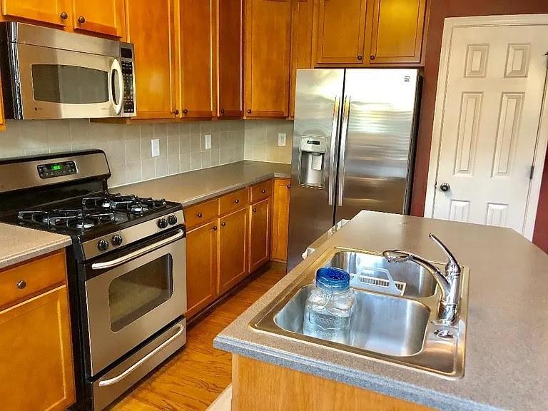 4363 Grove Field Park Northwest Suwanee, GA 30024 - Photo 11 of 18 a kitchen with stainless steel appliances granite countertop a stove a sink and a microwave