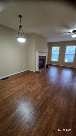 an empty room with wooden floor fireplace and windows