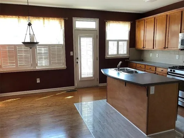 a kitchen with kitchen island a sink wooden floor and a large window