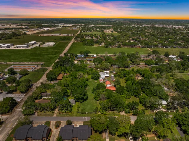 an aerial view of residential houses with outdoor space and trees