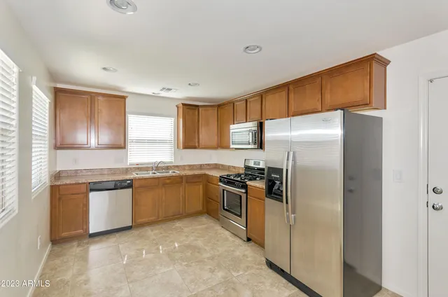 a kitchen with granite countertop stainless steel appliances a refrigerator stove top oven and sink