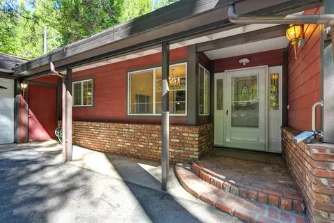 a view of an empty room with wooden floor fireplace and a window
