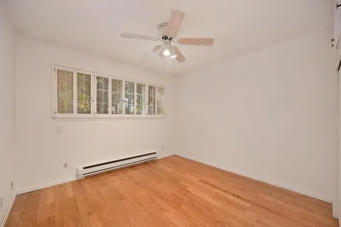 a view of a room with wooden floor and a ceiling fan