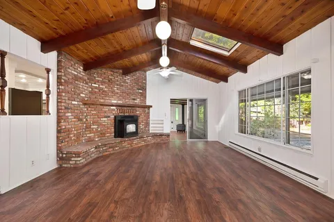 a view of an empty room with a window and fireplace