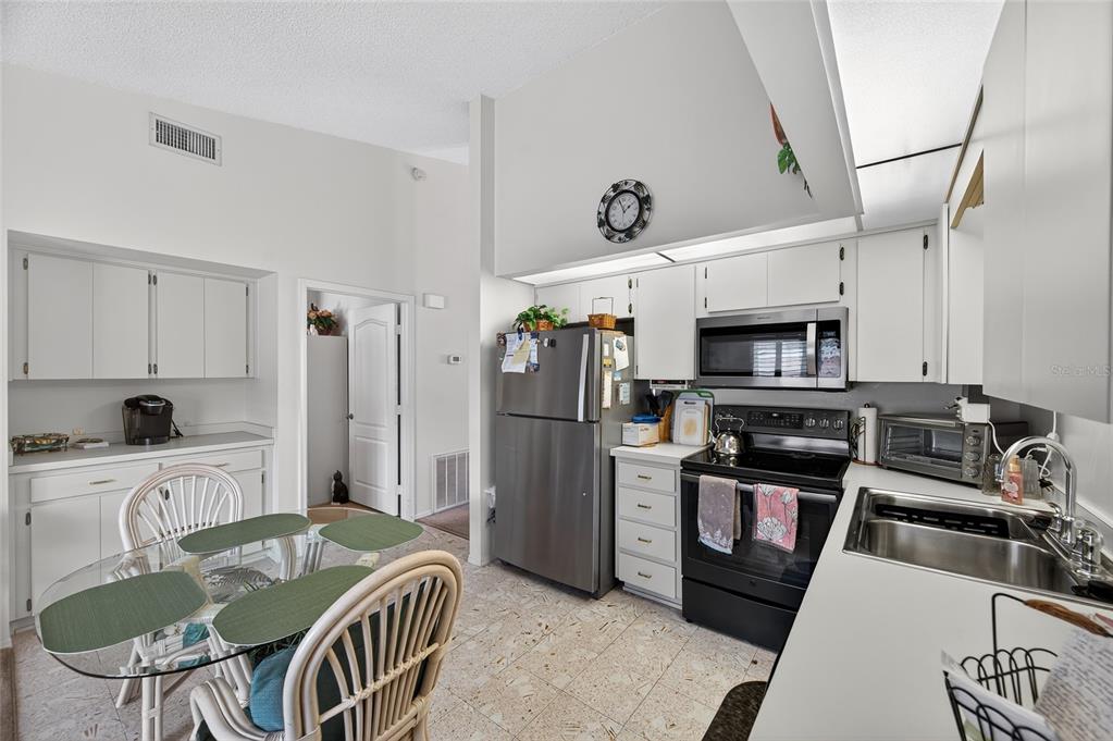2292 Austrian Lane, Unit 26 Clearwater, FL 33763 - Photo 8 of 27 a kitchen with stainless steel appliances granite countertop a refrigerator a stove a sink a dining table and chairs with wooden floor