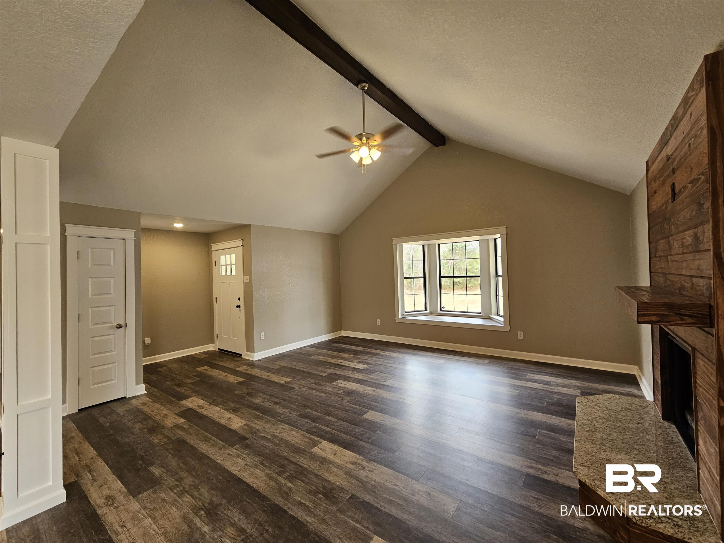 138 Wicker Way Daphne, AL 36526 - Photo 9 of 32 Unfurnished living room featuring a textured ceiling, beamed ceiling, dark wood-style floors, a large fireplace, and a ceiling fan