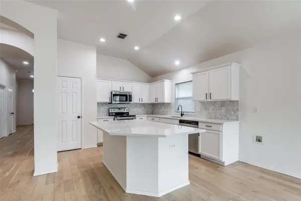 a kitchen with stainless steel appliances white cabinets a sink and a stove