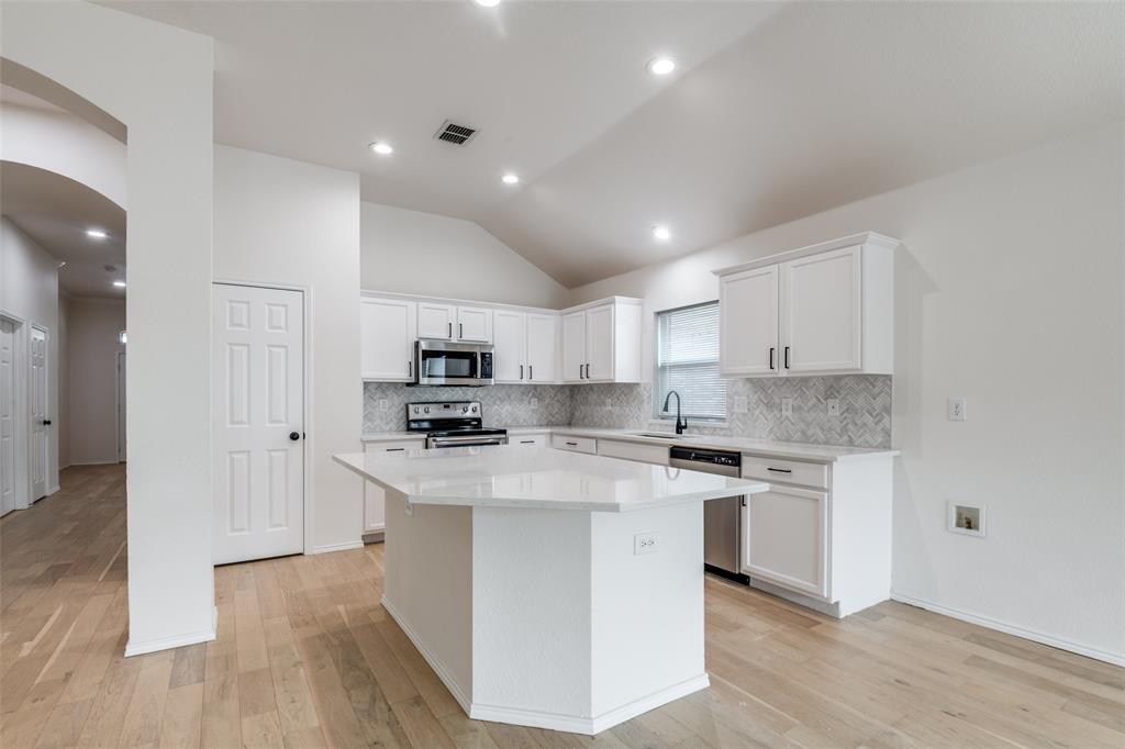 a kitchen with stainless steel appliances white cabinets a sink and a stove