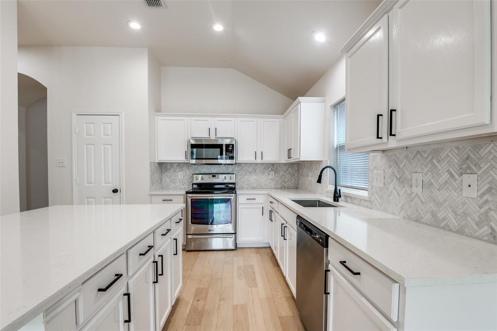 405 Hackberry Drive Fate, TX 75087 - Photo 7 of 24 a kitchen with stainless steel appliances sink a stove and cabinets