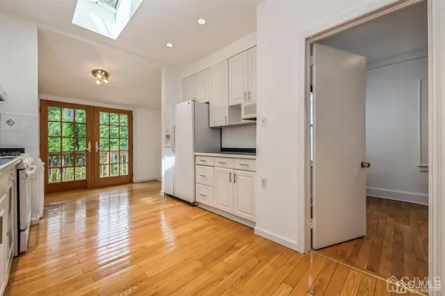 a open kitchen with white cabinets and wooden floor