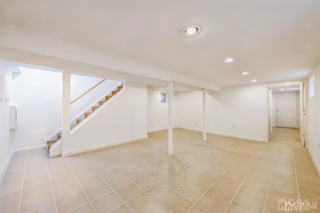 a view of an empty room with wooden floor and stairs