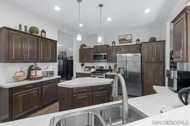 a kitchen with stainless steel appliances granite countertop a refrigerator a sink dishwasher a stove top oven a refrigerator with wooden cabinets and floor