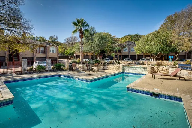a swimming pool view with a seating space and a garden view