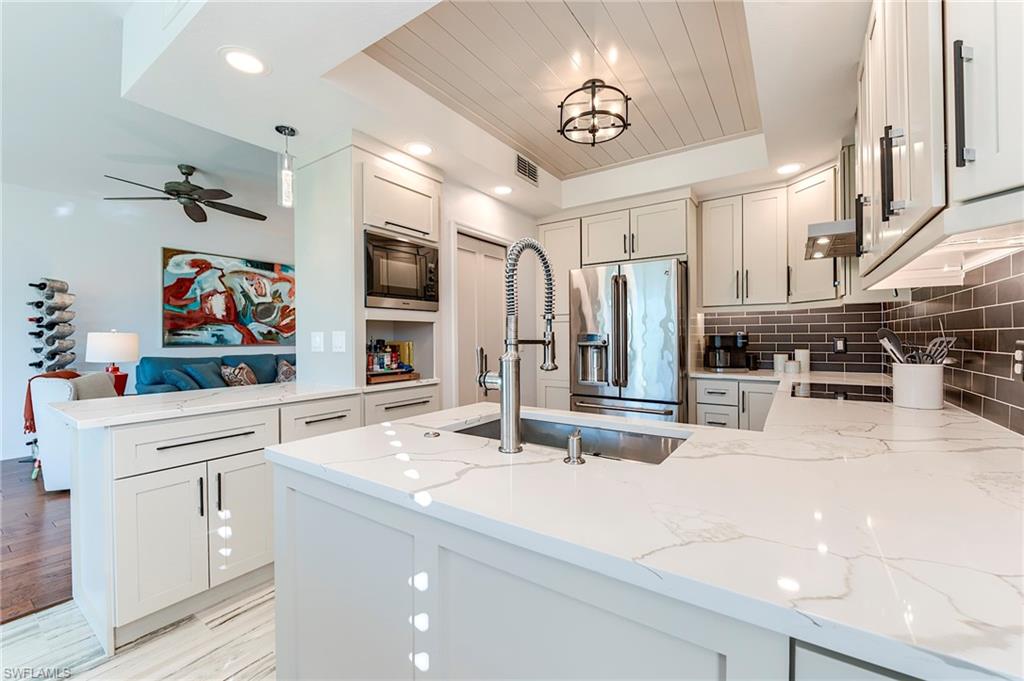 9241 Palmetto Ridge Drive, Unit 101 Estero, FL 34135 - Photo 11 of 28 a kitchen with stainless steel appliances kitchen island granite countertop a sink and cabinets