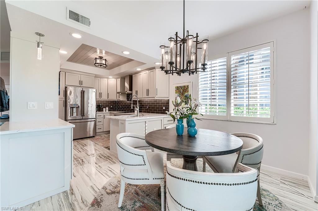9241 Palmetto Ridge Drive, Unit 101 Estero, FL 34135 - Photo 14 of 28 a kitchen with stainless steel appliances a dining table and chairs