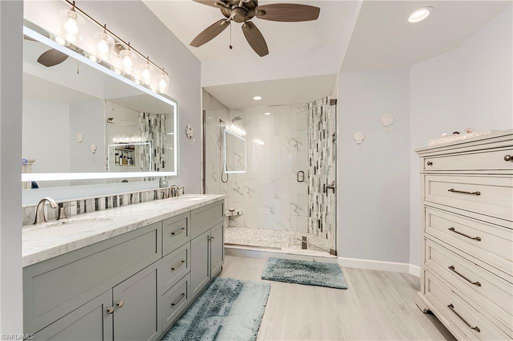 9241 Palmetto Ridge Drive, Unit 101 Estero, FL 34135 - Photo 18 of 28 a bathroom with a double vanity sink a toilet a mirror and shower