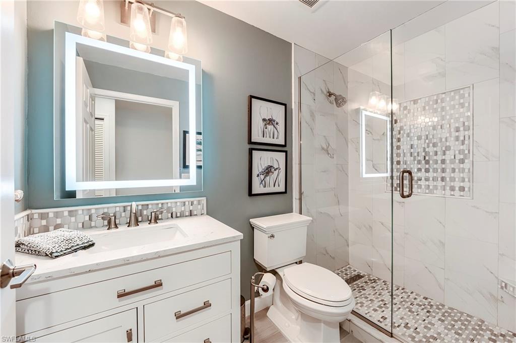 9241 Palmetto Ridge Drive, Unit 101 Estero, FL 34135 - Photo 23 of 28 a bathroom with a granite countertop sink a toilet and a mirror