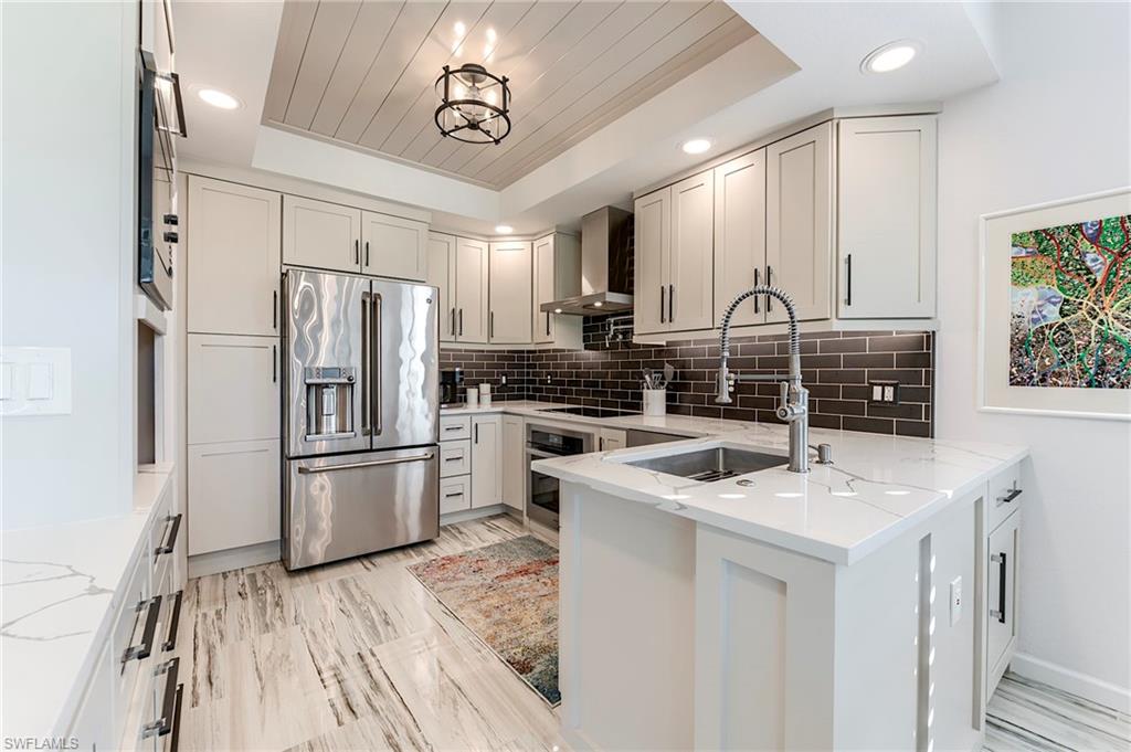9241 Palmetto Ridge Drive, Unit 101 Estero, FL 34135 - Photo 10 of 28 a kitchen that has a refrigerator a stove a microwave and a dining table