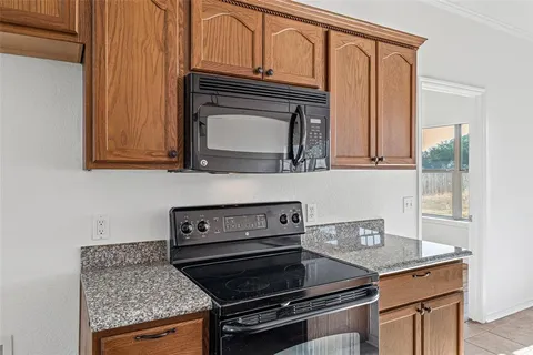 a kitchen with granite countertop a stove top oven cabinetry and granite counter tops