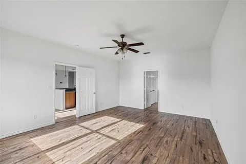 an empty room with wooden floor and ceiling fan