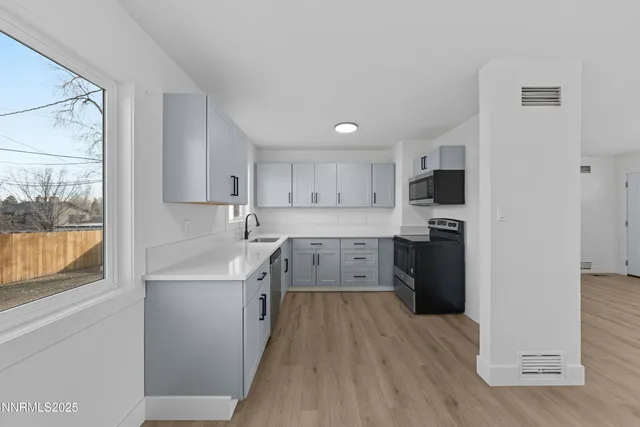 a kitchen with stainless steel appliances a sink a stove a refrigerator cabinets and a window