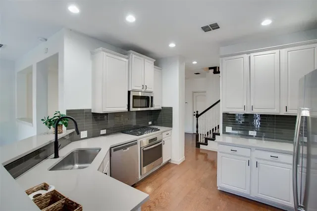a kitchen with white cabinets a sink stove and refrigerator