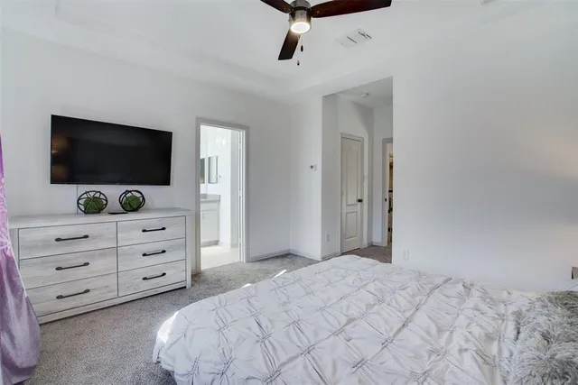 a bedroom with a bed and a flat tv screen on dresser