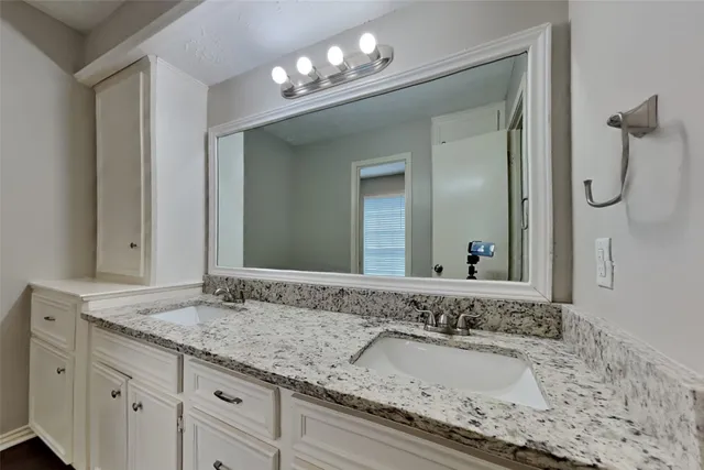 a bathroom with a granite countertop double vanity sink and a mirror