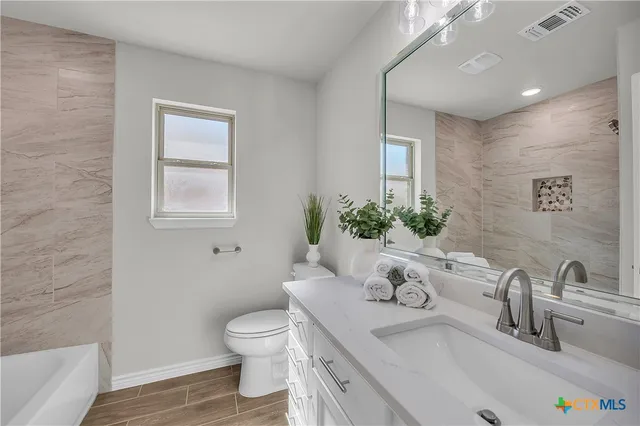 a bathroom with a granite countertop sink a toilet and a mirror