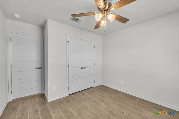 an empty room with wooden floor a ceiling fan and closet area