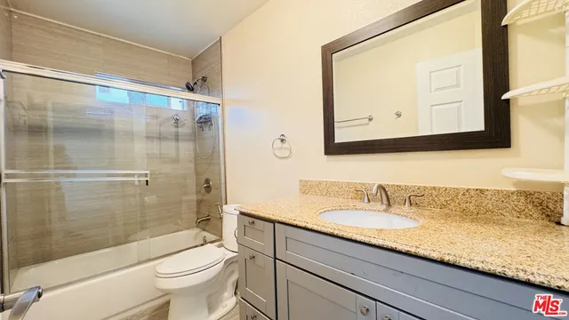a bathroom with a granite countertop sink a toilet and a shower