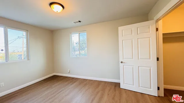 an empty room with wooden floor and windows