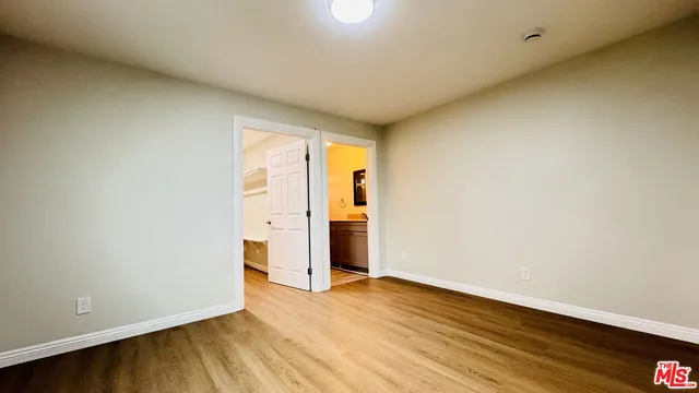 a view of an empty room with wooden floor and closet