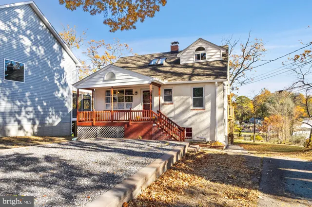 a view of a white house with a large tree and wooden fence