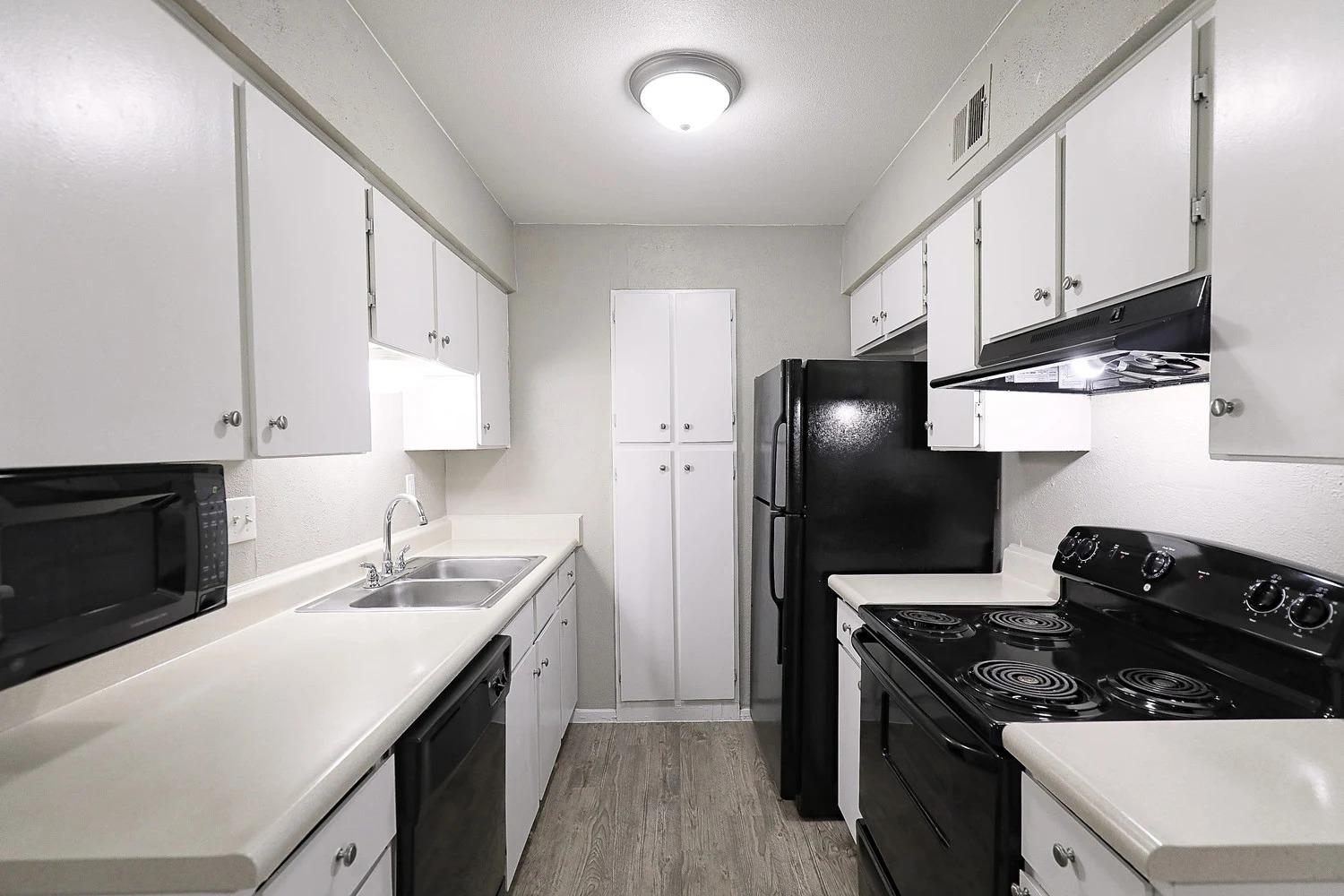 8100 North Mopac Expressway, Unit 2107 Austin, TX 78759 - Photo 15 of 23 Kitchen with black appliances, white cabinetry, light countertops, and under cabinet range hood