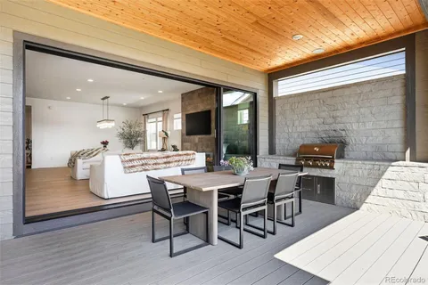 a dining hall with stainless steel appliances granite countertop a stove a sink a dining table and chairs with wooden floor