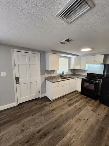a large white kitchen with a stove a sink and dishwasher with wooden floor